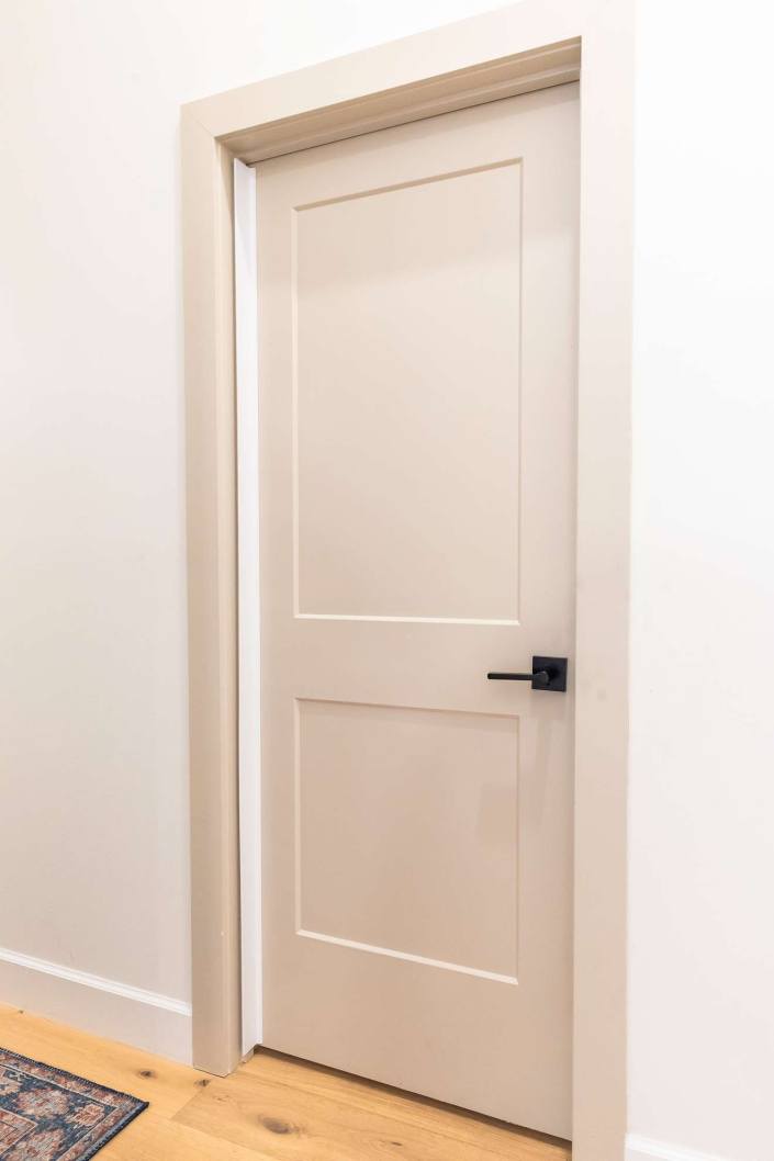 White Adhesive Fingersafe guard installed on the hinge side of a closed interior door.